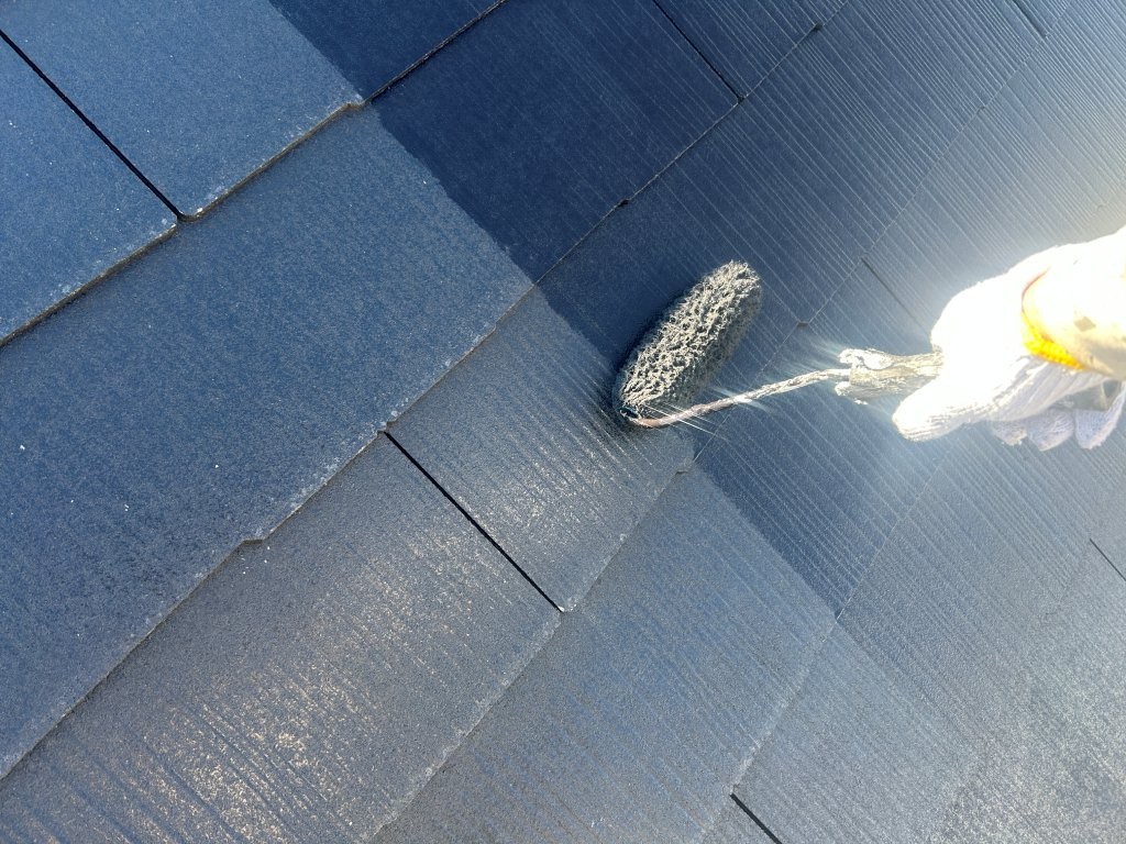 屋根中塗り作業の様子。八潮市S様邸でブラック系塗料を塗布している工程